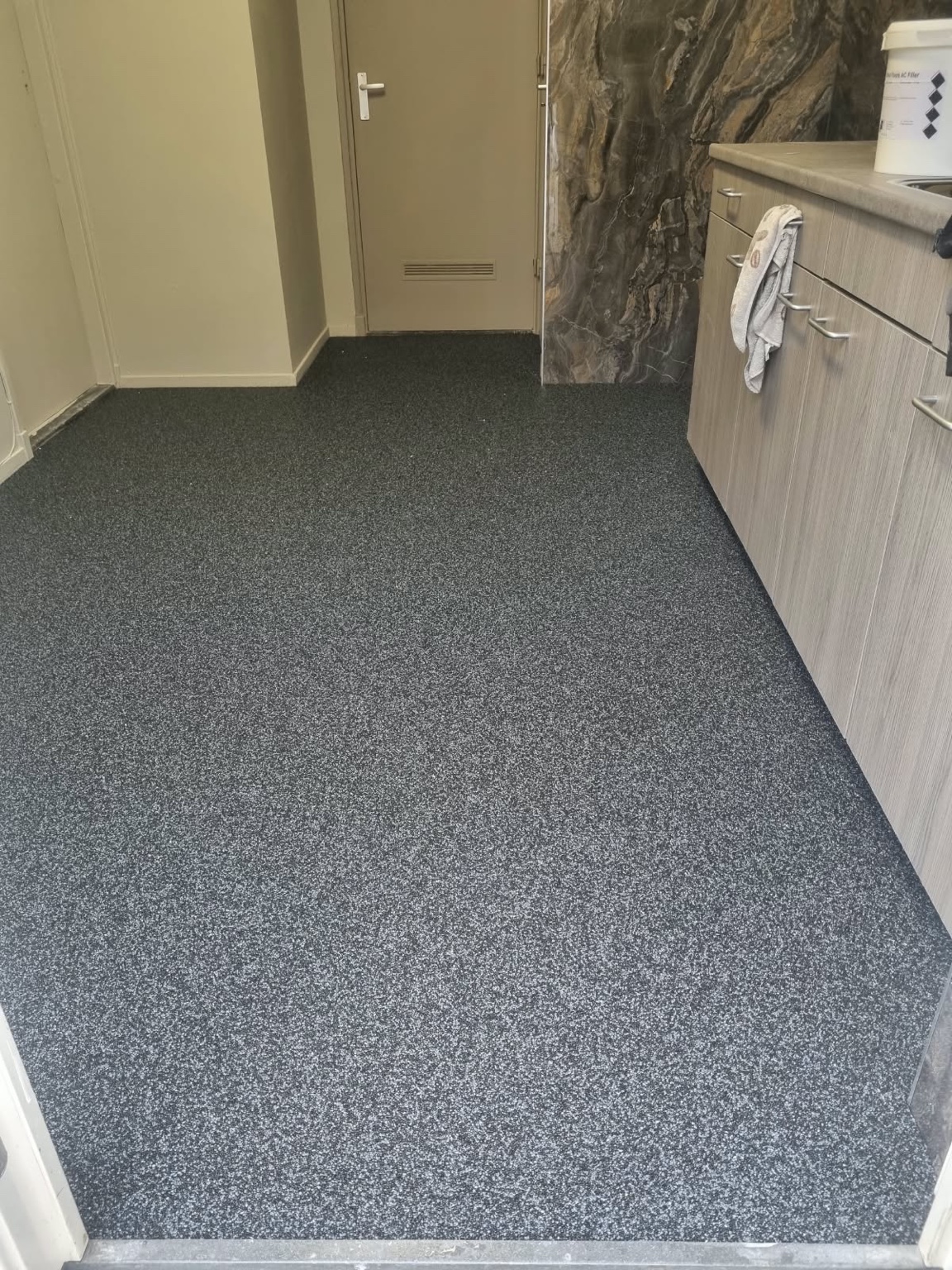 Donker gemêleerde epoxy grindvloer in de keuken van een particuliere woning in Roermond