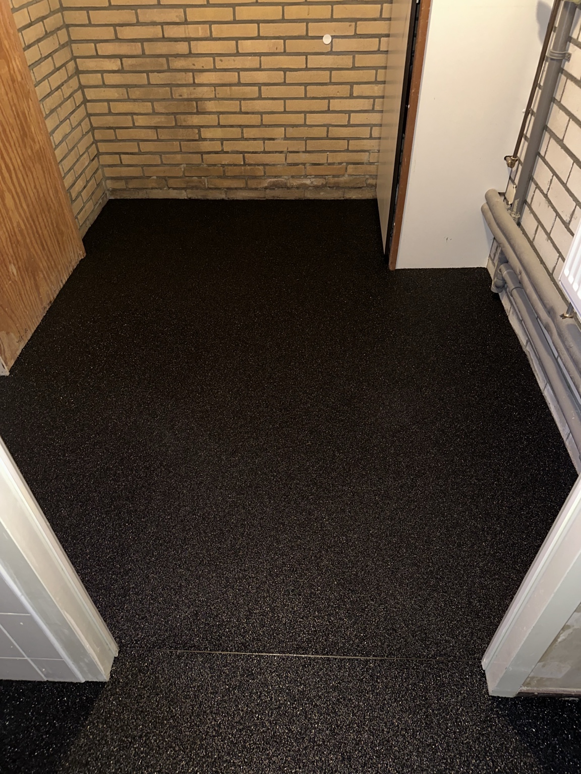 Donkere epoxy-steentapijtvloer in het washok van een particuliere woning in Kampen