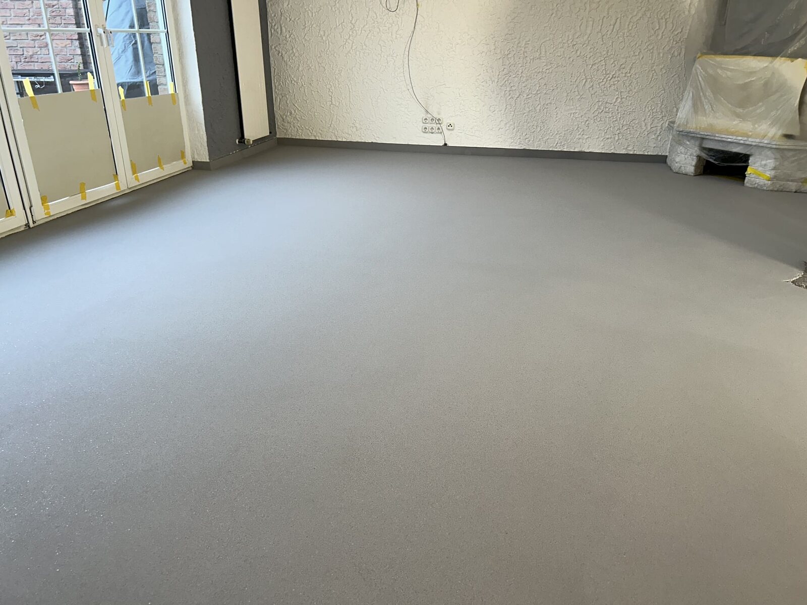 Strakke grijze epoxy troffel- en mortelvloer in de woonkamer van een particuliere woning