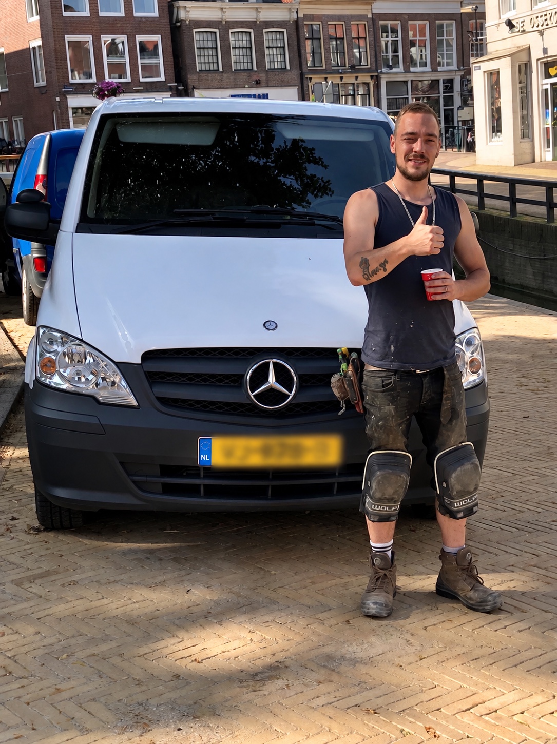 Kenye Mertens in werkkleding voor zijn bedrijfsbus met het kenteken onleesbaar gemaakt