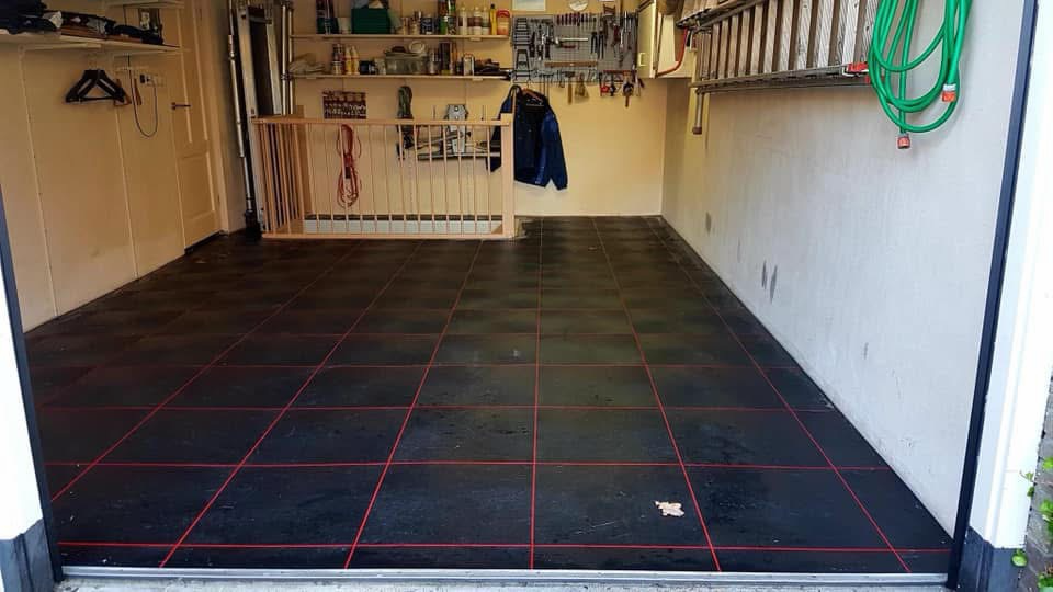 Donkere PVC-bedrijfsvloer met rode voegen in een particuliere garage