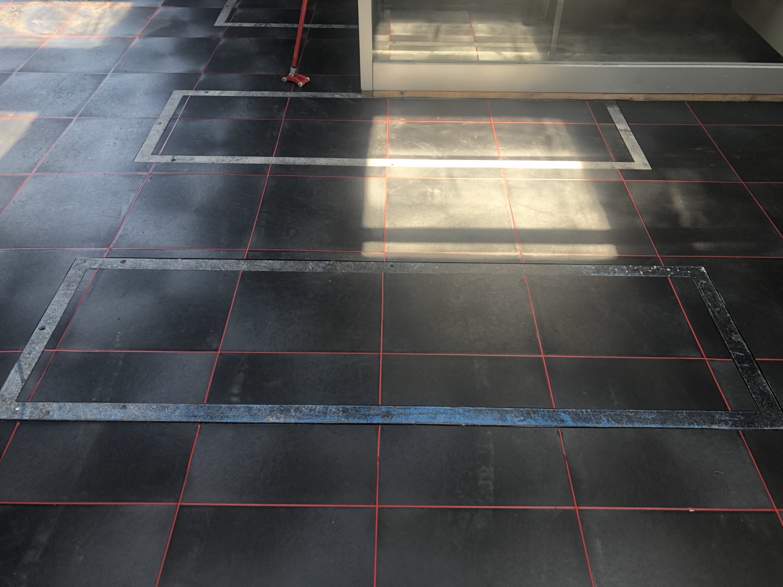 PVC-bedrijfsvloer nauwkeurig afgewerkt rondom voorzieningen in een autogarage