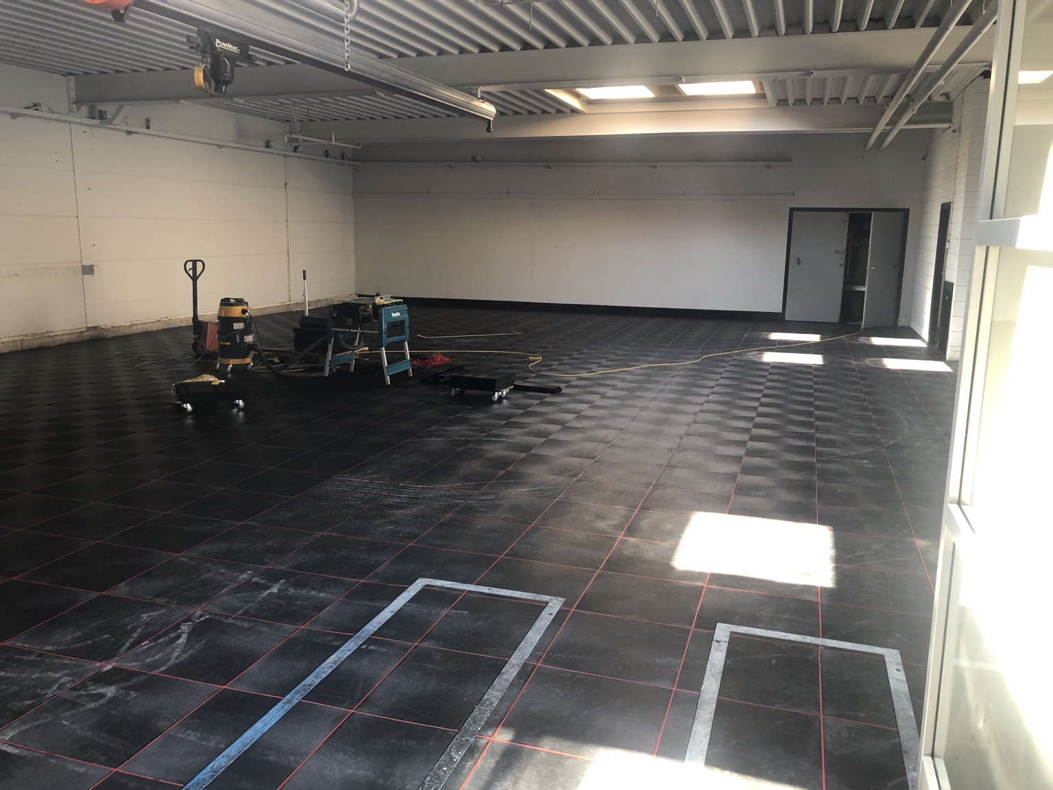 Overzicht van een professionele autogarage met zwarte PVC-bedrijfsvloer en rode lasvoegen