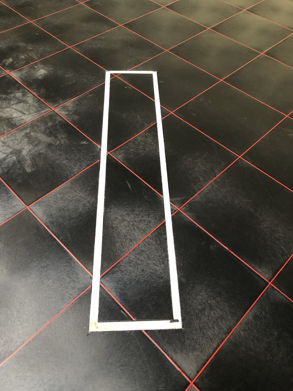 Detail van strak afgewerkte rode lasvoegen tussen zwarte PVC-vloertegels