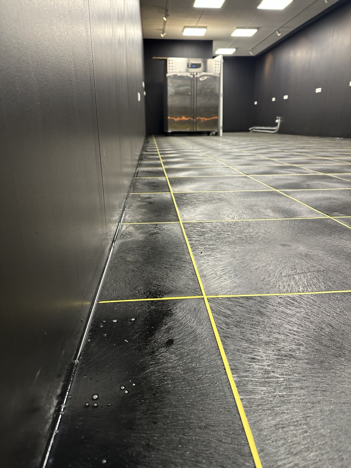 Detail van de strak afgewerkte gele lasvoegen in de PVC-bedrijfsvloer